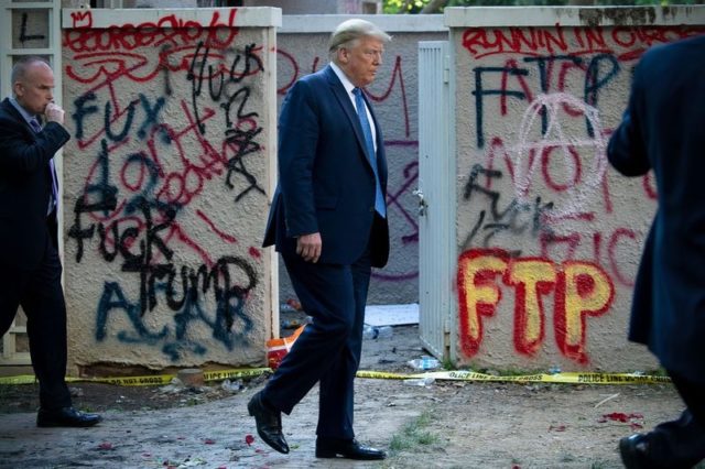 President Donald Trump walks past trashed streets and graffiti including one that says "Fuck Trump" on his way to a photo op in front of St. John's Church.