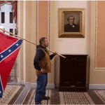 In one of the most shocking scenes of the Jan 6th US Capitol insurrection, a man is seen carrying the confederate flag into the Capitol