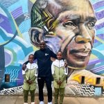 Eliud Kipchoge Mural With son in front of a mural in his honor