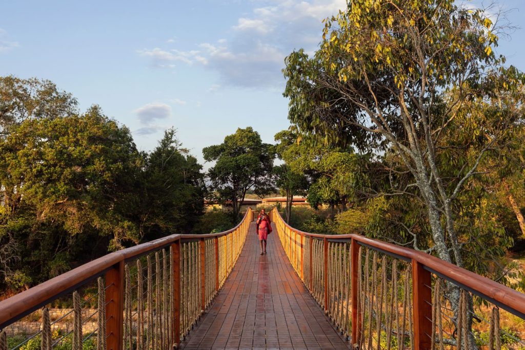 A guest crosses a raised wooden footbridge that connects the lodge areas at the Ritz-Carlton Maasai Mara Safari Camp. Courtesy of Ritz-Carlton Hotel.