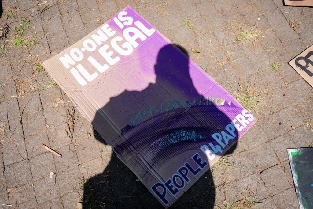 A handmade sign reading "No-One Is Illegal, From Cape & Cairo... People B4Papers" at Siyafana Sonke's Heritage Day walk and festival, Sept. 24.